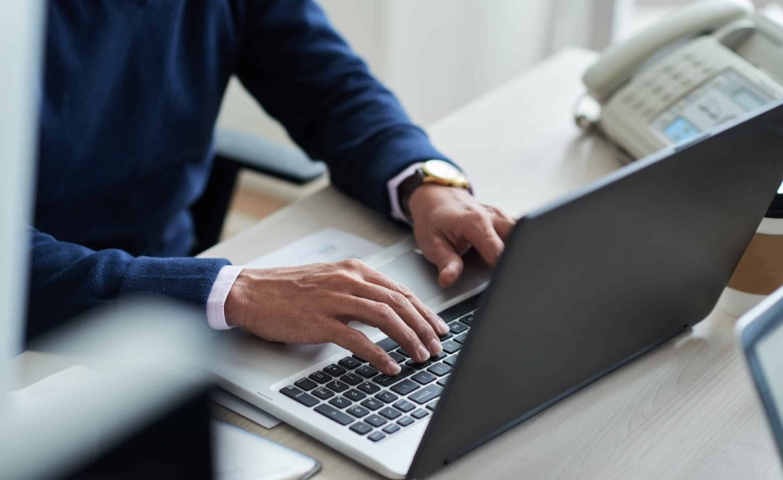 Close-up image of businessman typing on laptop at his workplace