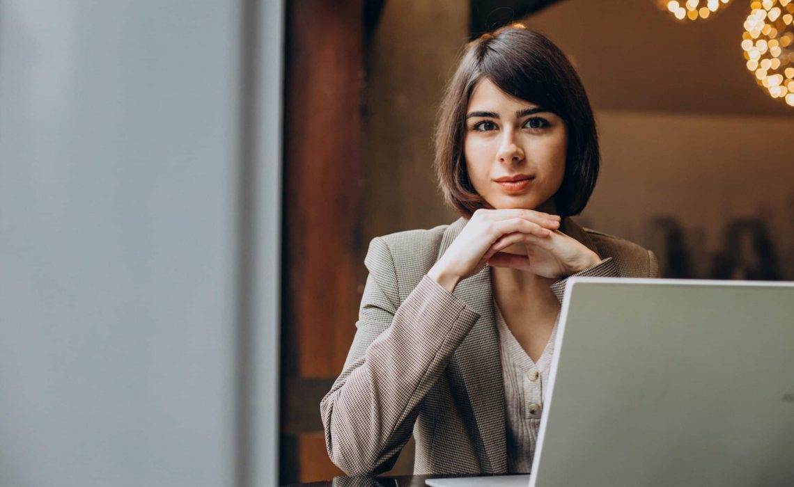 Young business woman working on laptop in a cafe
