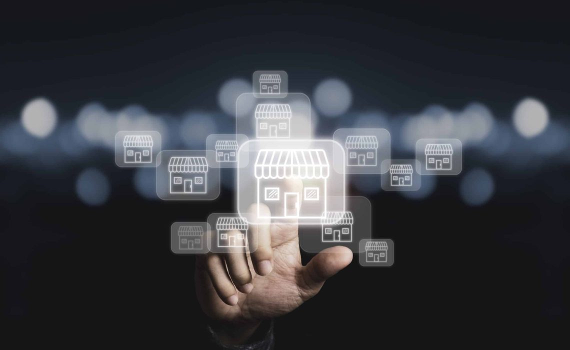 Businessman hand pointing to virtual shopping store which connection line with others small shopping stores , expand and development franchise concept.