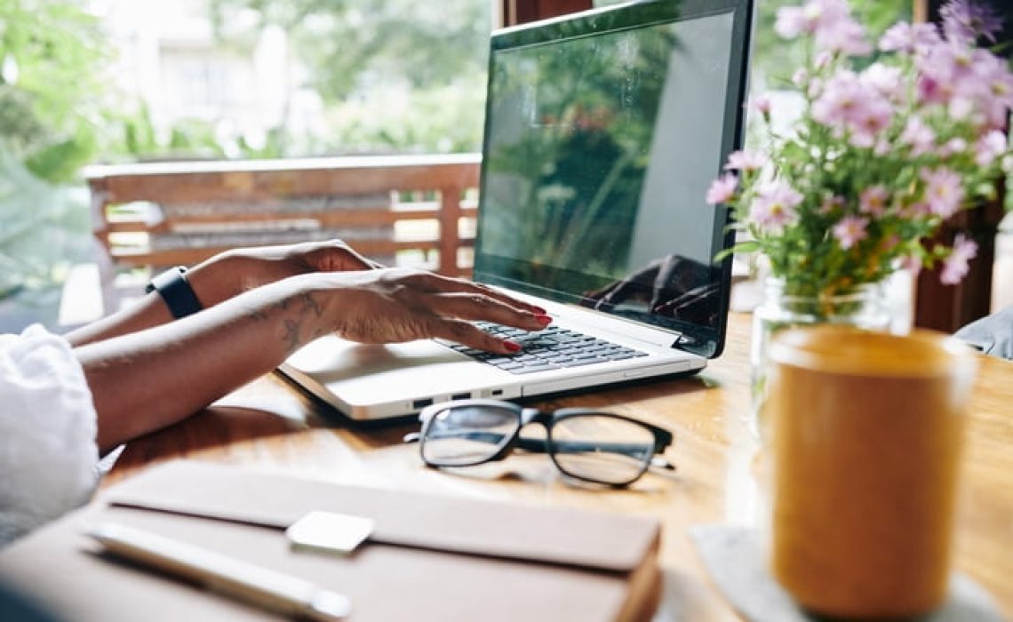Close-up of African businesswoman sitting at the table and working on laptop at home
