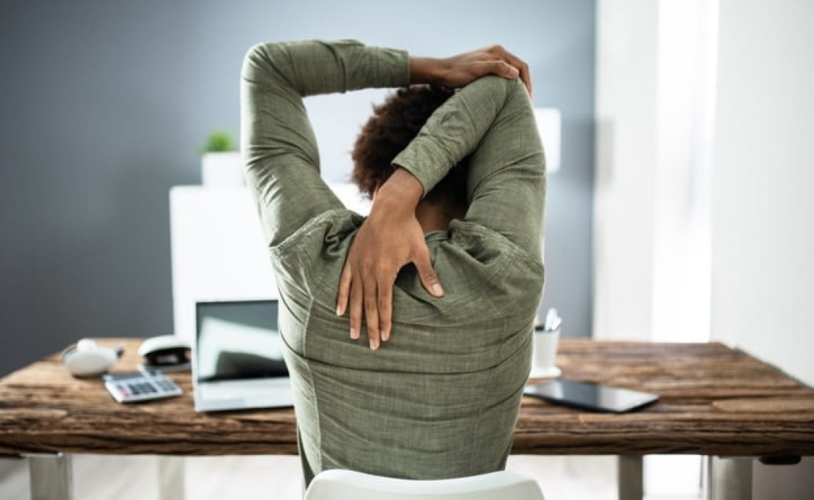Rear View Of A Businessman Stretching His Arms In Office