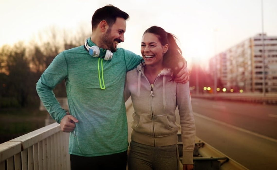 Young attractive couple running outside on sunny day Young attractive and cheerful couple running outside on sunny day