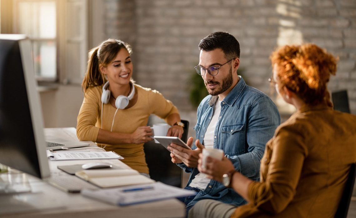 Team of young entrepreneurs having a business meeting in the office. Focus is on businessman using digital tablet.
